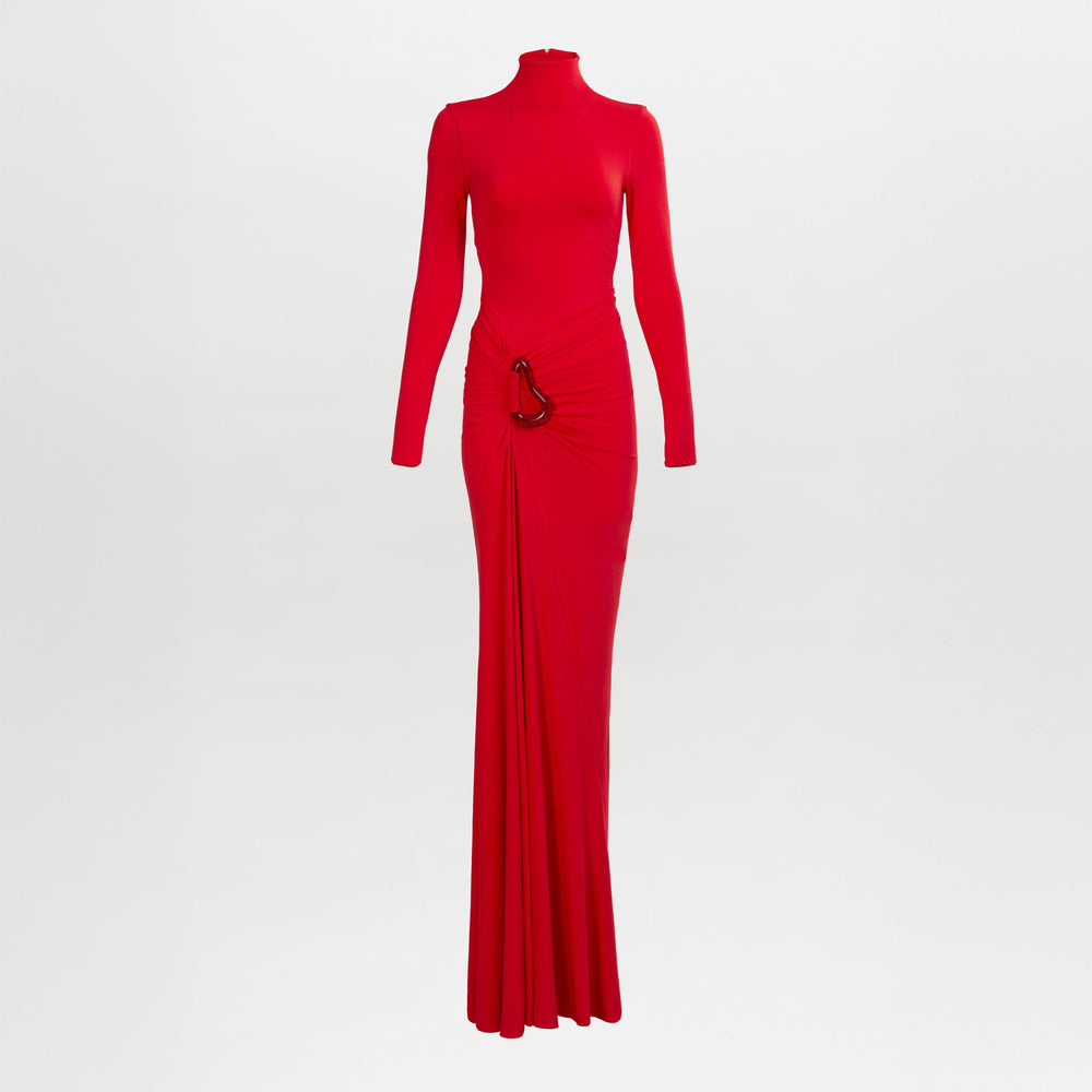 El vestido Lena es un vestido rojo de manga larga y largo hasta el suelo con escote alto, detalle fruncido en la cintura y un detalle metálico en un lateral. Está fotografiado sobre un fondo blanco liso.