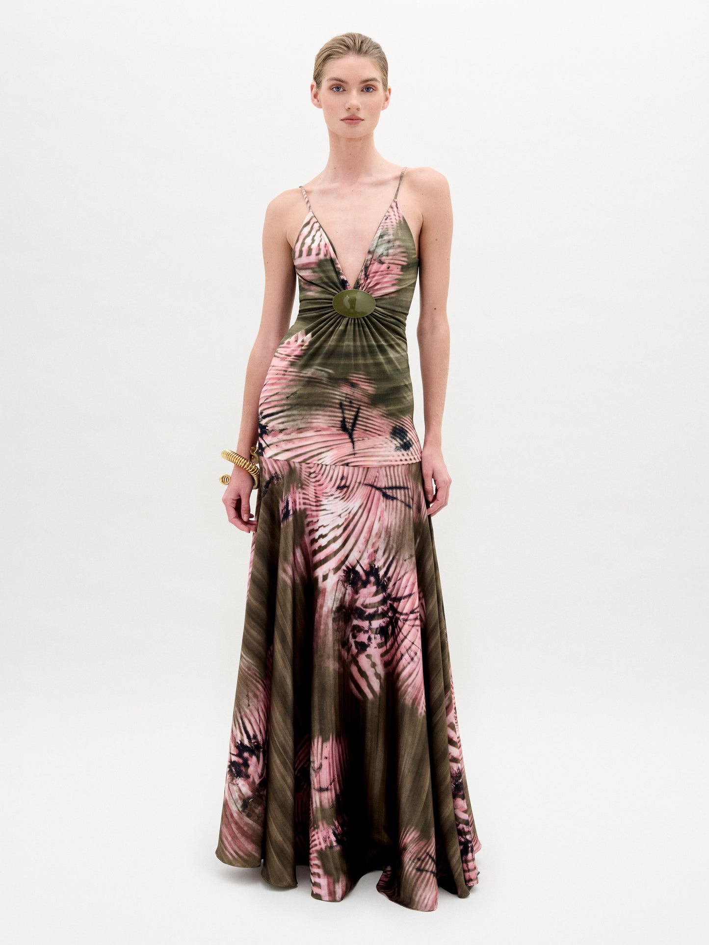 Sobre un fondo blanco liso, una persona luce el vestido Carmin, un maxi vestido con escote en V y teñido en verde oliva y rosa, confeccionado en tejido italiano. El vestido tiene un corpiño ajustado y una falda acampanada.
