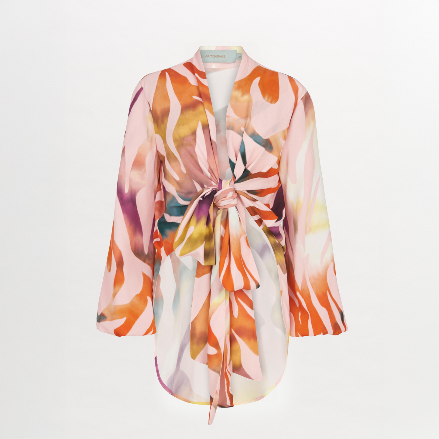 El Blusa Honey Blush Prismatic es un albornoz de manga larga y largo hasta la rodilla con un estampado abstracto multicolor en tonos rosas, naranjas y morados y cierre de lazo delantero, que hace gala de un estilo vibrante.