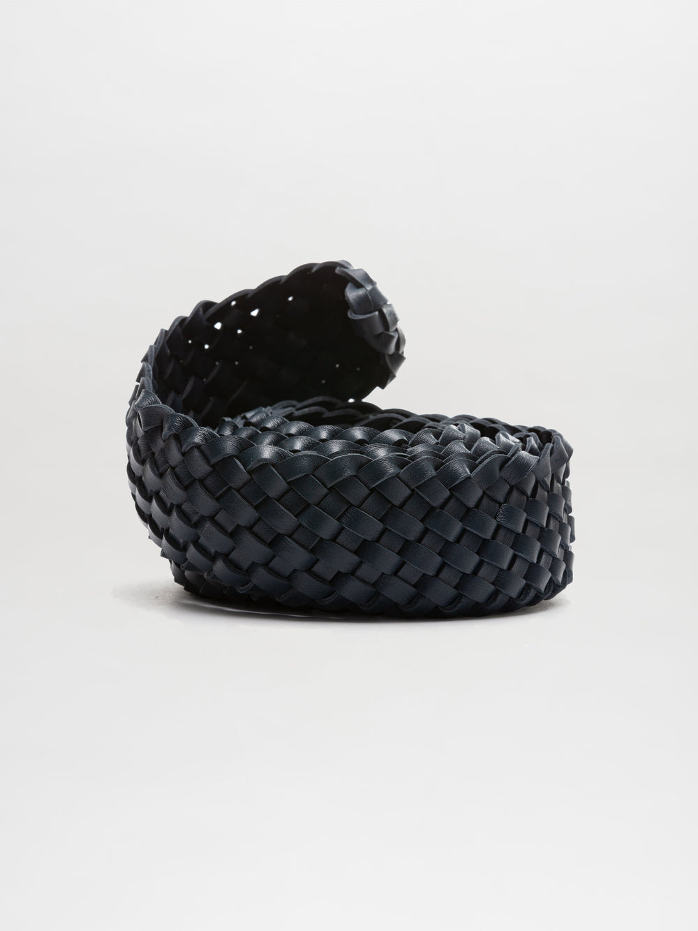 El Cinturón Lauren, un cinturón de cuero trenzado negro en espiral elaborado con cuero italiano de calidad, reposa sobre un fondo blanco liso. Su diseño trenzado con textura está parcialmente desenrollado para revelar su intrincado patrón.