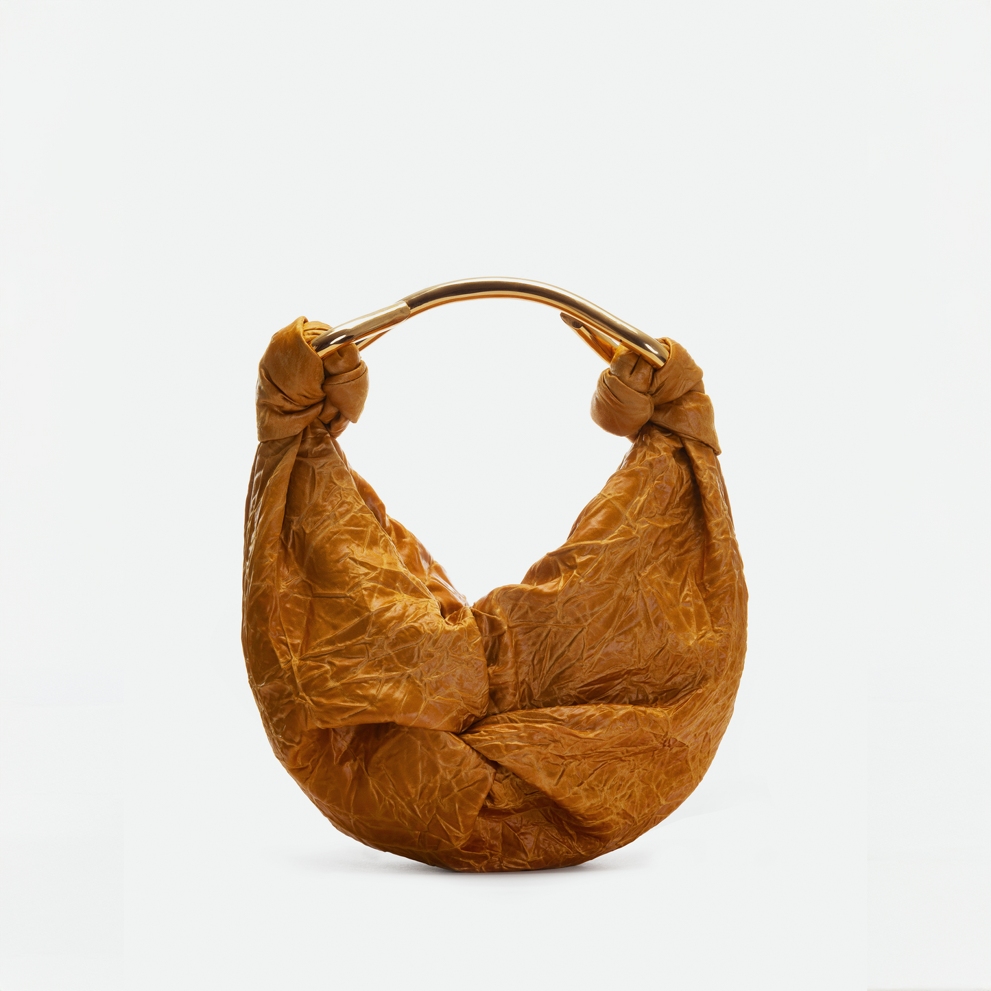 El Bolso Sofia Small es una cartera pequeña de color marrón con textura, forma redondeada, detalles anudados en la parte superior y un asa metálica curva, hecha en Colombia y presentada sobre un fondo blanco liso.