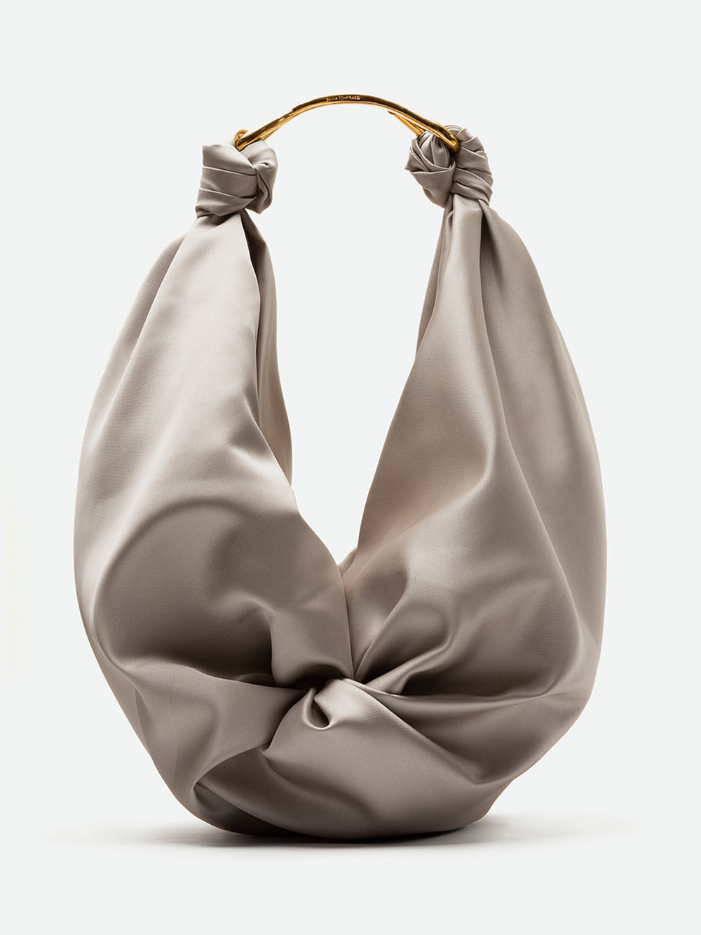 El Bolso Sofia Maxi es un bolso hobo suave, de color gris claro, con un asa curva dorada. Fabricado en Colombia, su tela está fruncida y anudada en la parte superior a ambos lados para lograr un aspecto drapeado y escultural.