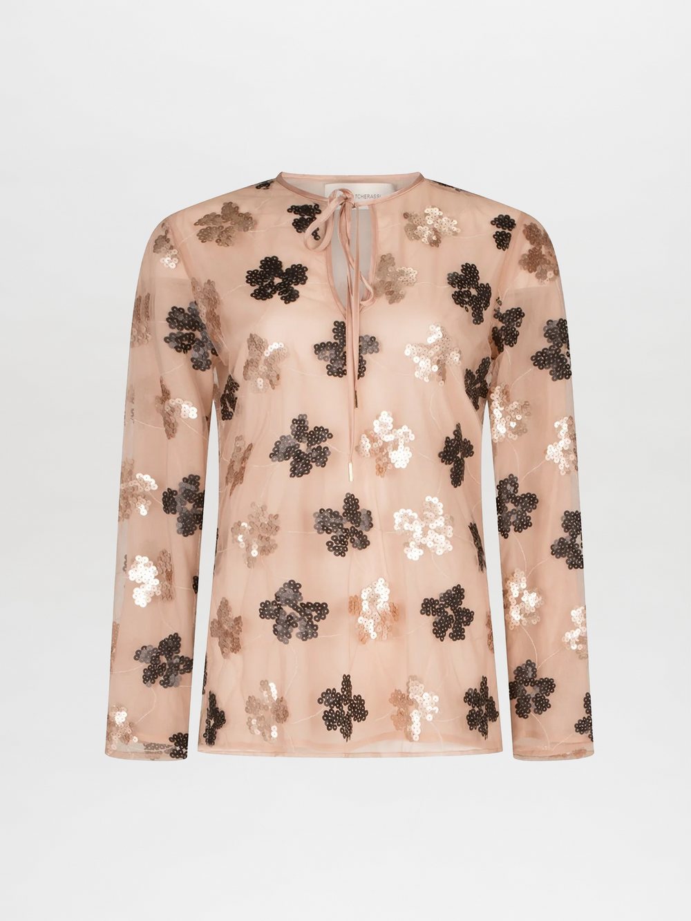 La Blusa Tosca es una blusa beige transparente de manga larga hecha en Colombia, que presenta patrones florales de lentejuelas brillantes en tonos oscuros y claros, un escote redondo y un cierre de lazo en el cuello.