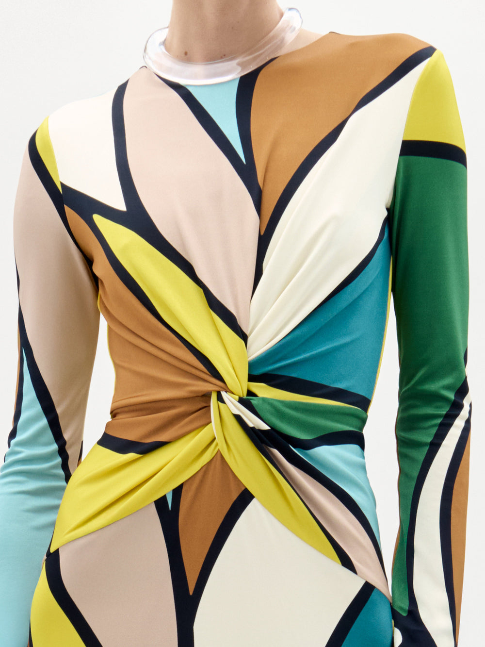 Una persona lleva el Vestido Lucian, un maxi de manga larga con atrevido estampado geométrico multicolor y cintura con nudo. Confeccionado en tejido italiano, presenta escote redondo con ribete translúcido. La cabeza de la persona no es totalmente visible.