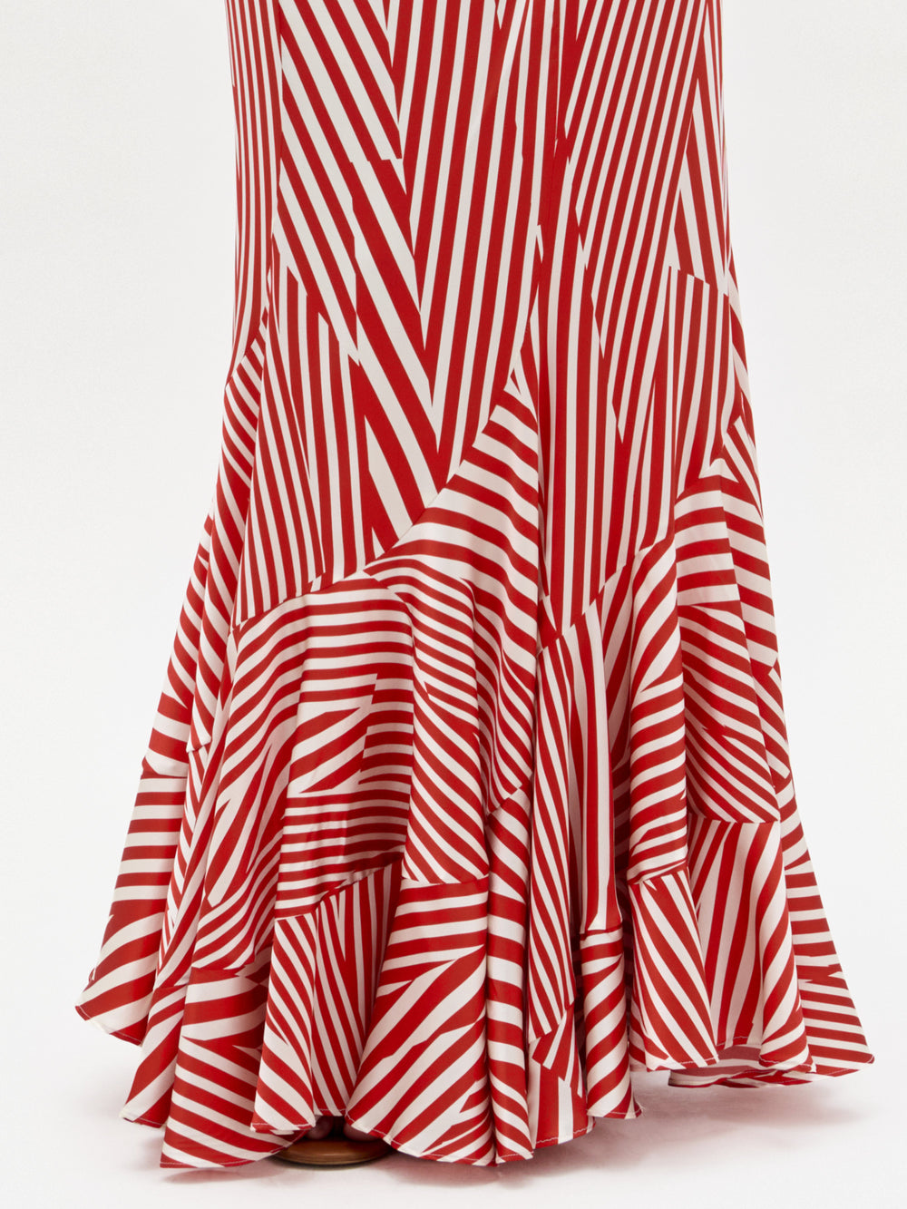 Detalle de la parte inferior de la falda Florina, un modelo maxi con rayas diagonales rojas y blancas y bajo acampanado con volantes, sobre fondo blanco.