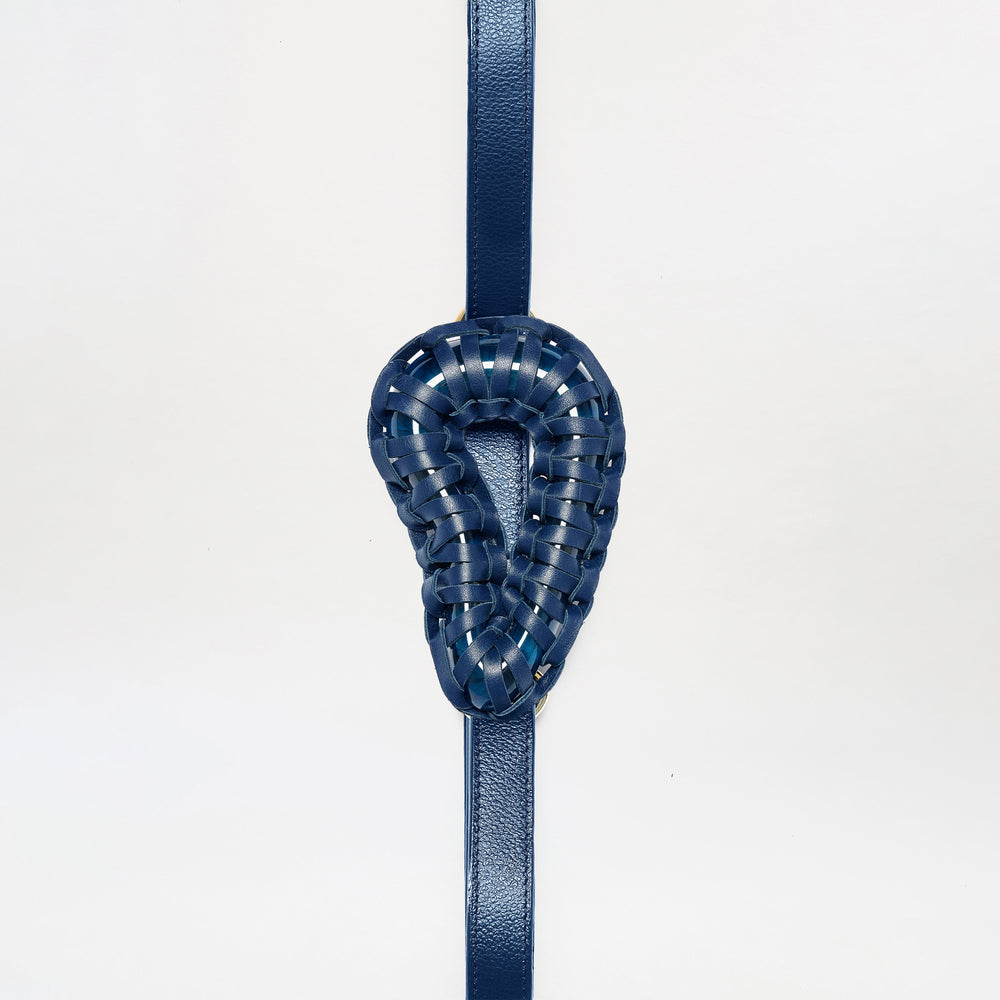 The Renata Belt is a blue leather strap featuring a woven, ear-shaped blue leather centerpiece, shown vertically against a plain white background.