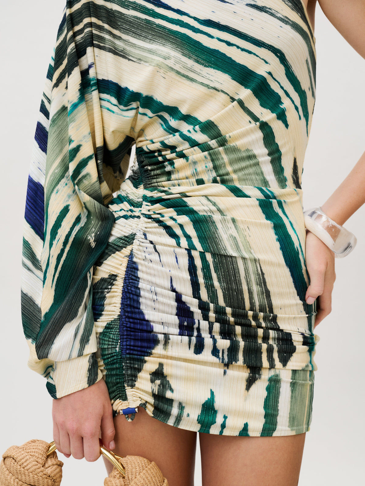 Adelaide Dress, a one-shoulder mini dress in Italian fabric featuring green, blue, and cream brushstroke patterns with a ruched side seam.