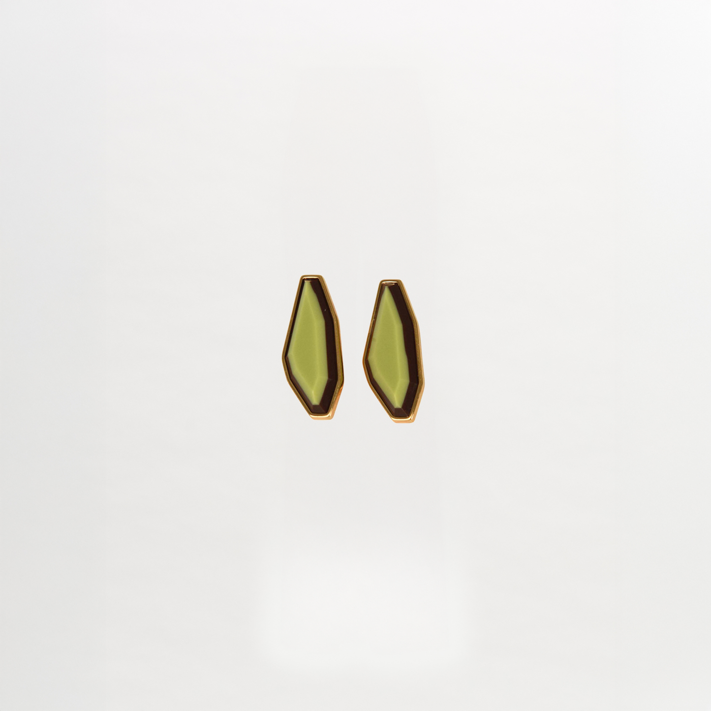 Un par de Aretes Badra Lime con centros de piedras de fantasía de color verde oliva engastados en marcos de metal de color dorado, bellamente exhibidos sobre un fondo blanco liso.