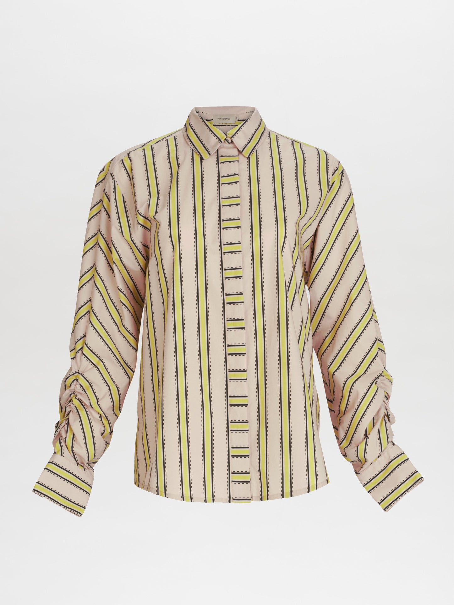 La Blusa Caritina es una camisa de manga larga abotonada con rayas verticales en tonos beige, amarillo y negro. Confeccionada con tela italiana de primera calidad, presenta un cuello clásico y mangas fruncidas. Fabricada en Colombia, muestra una meticulosa atención a los detalles sobre un fondo blanco liso.