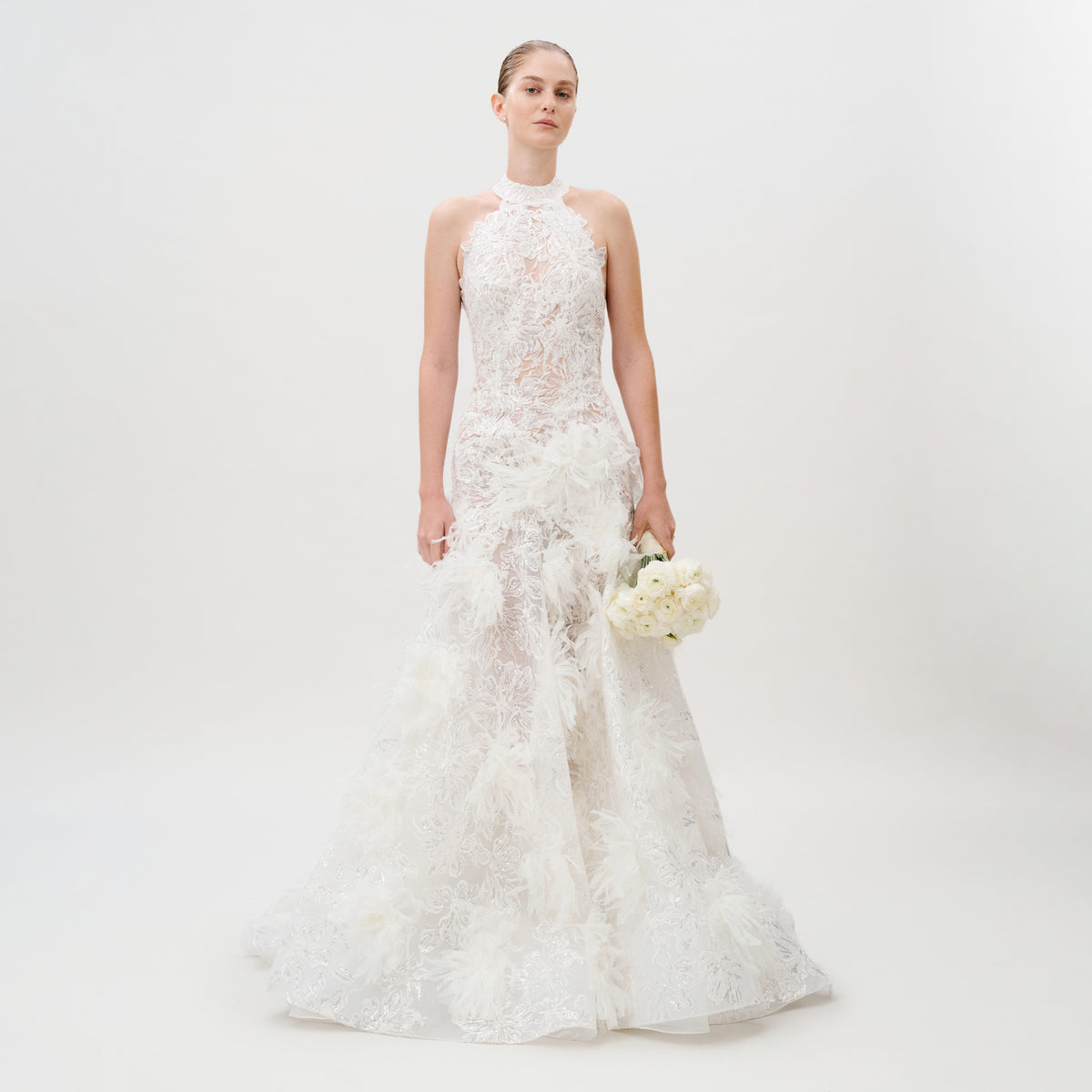 Dressed in the Darsha Dress, featuring delicate white lace and elegant silk trim, a person holds a bouquet of white flowers while standing against a plain white background.