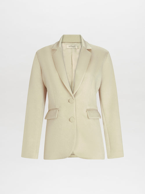 La Chaqueta Echo es un blazer entallado beige para mujer, con solapas con muescas, dos botones delanteros, mangas largas y confeccionado en tela italiana fina con dos bolsillos con solapa. Se presenta elegantemente sobre un fondo blanco.