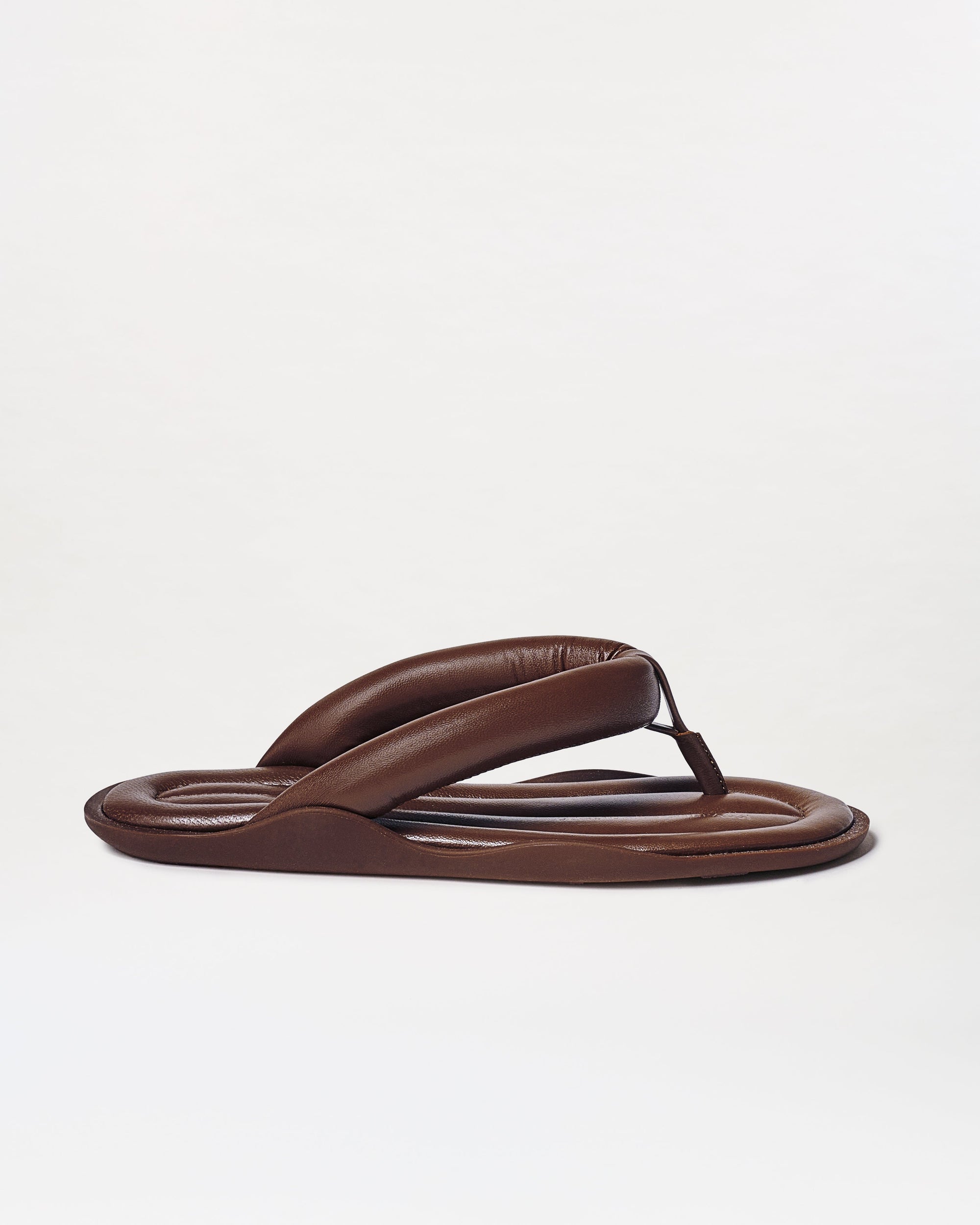The Harper Sandals are brown padded flip-flops featuring thick, cushioned straps and a rounded sole, shown on a plain white background.
