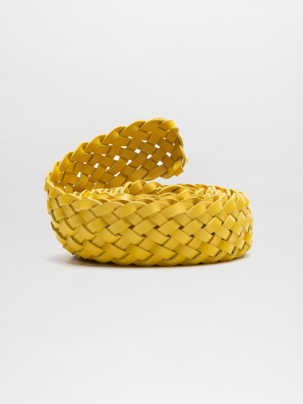 El Cinturón Lauren, un tejido trenzado de color amarillo que evoca la artesanía del cuero fino, está centrado sobre un fondo blanco. El trenzado está tejido de manera uniforme en una pila circular con un extremo desenrollado y elevado, capturando la elegancia del diseño del cuero italiano.