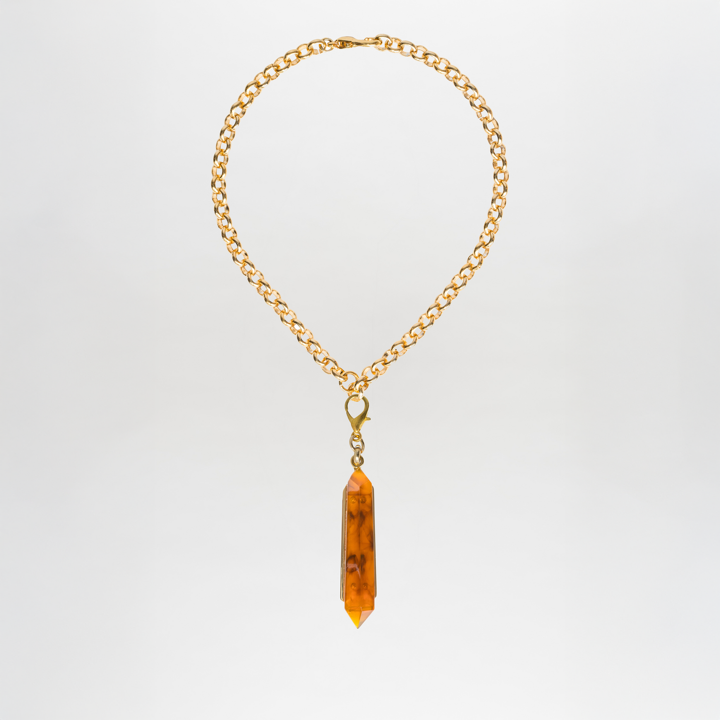 Collar Mariela: gargantilla de latón bañado en oro con colgante de cristal ámbar y gran punta central, presentado sobre fondo blanco sencillo.