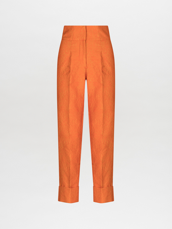 Pantalón Moad de color naranja, de tiro alto, confeccionado en tejido jacquard texturizado, con dobladillo con puños y sobre un fondo blanco liso. Hecho en Colombia.