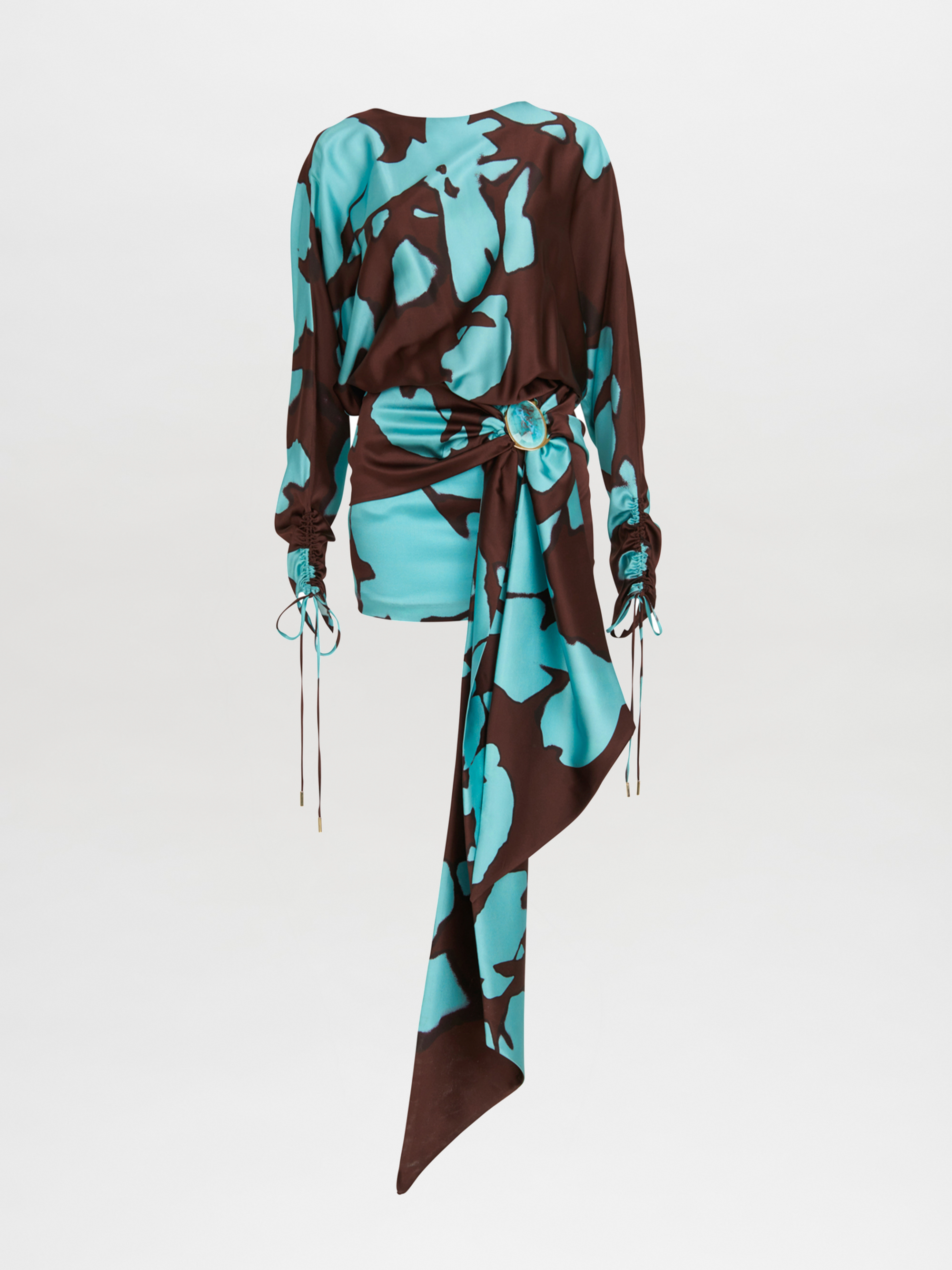 El vestido Mallorca Celeste Cacao presenta un estampado floral abstracto azul y marrón, mangas fruncidas con lazos y una faja drapeada asimétrica en la cintura, sobre un fondo blanco.