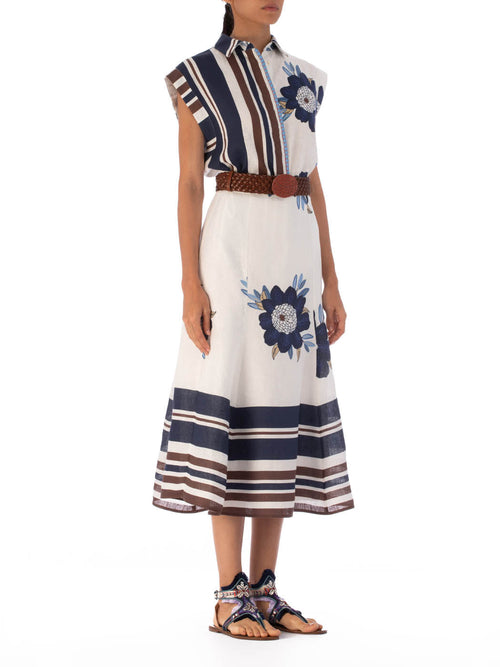 The Rina Blouse Multi Navy Brown Floral is a sleeveless linen top showcasing blue and brown vertical stripes on one side, with fringe detailing and blue floral patterns on a white background on the other side.