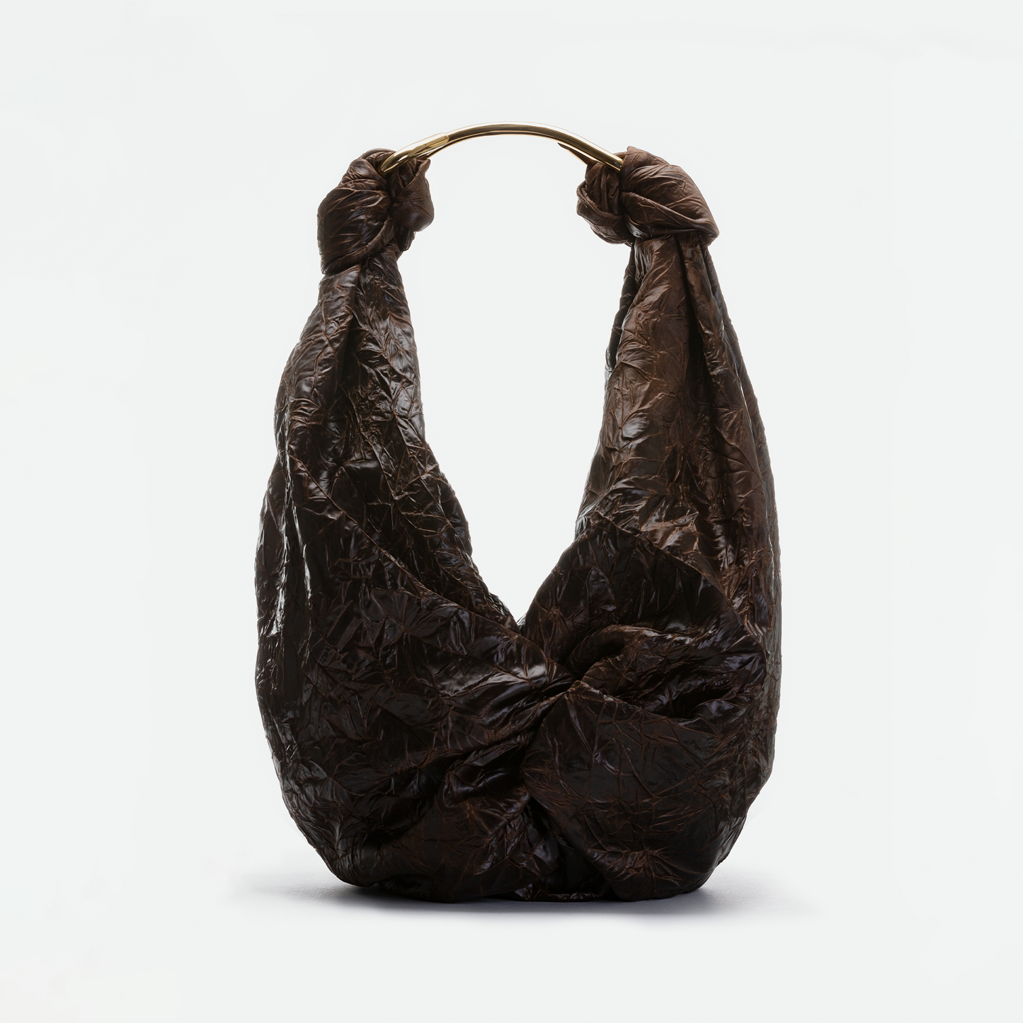El bolso Sofía (Maxi) es un bolso marrón arrugado fabricado en Colombia con asa de metal brillante, dos grandes nudos superiores, confeccionado en tejido italiano de primera calidad y mostrado sobre un fondo blanco liso.