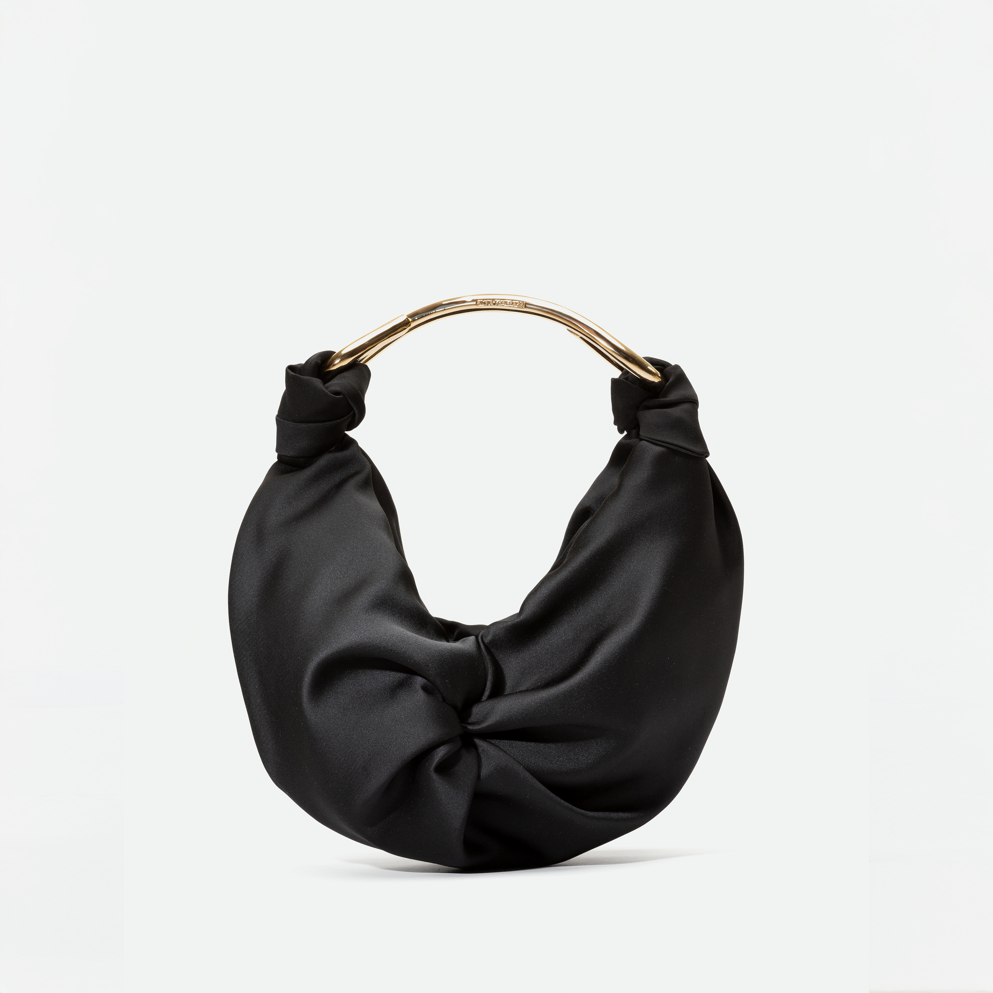 El Bolso Sofia Small es una cartera pequeña hecha en Colombia con textil italiano negro satinado, diseño fruncido tipo nudo y asa curva de metal dorado, mostrada sobre fondo blanco.