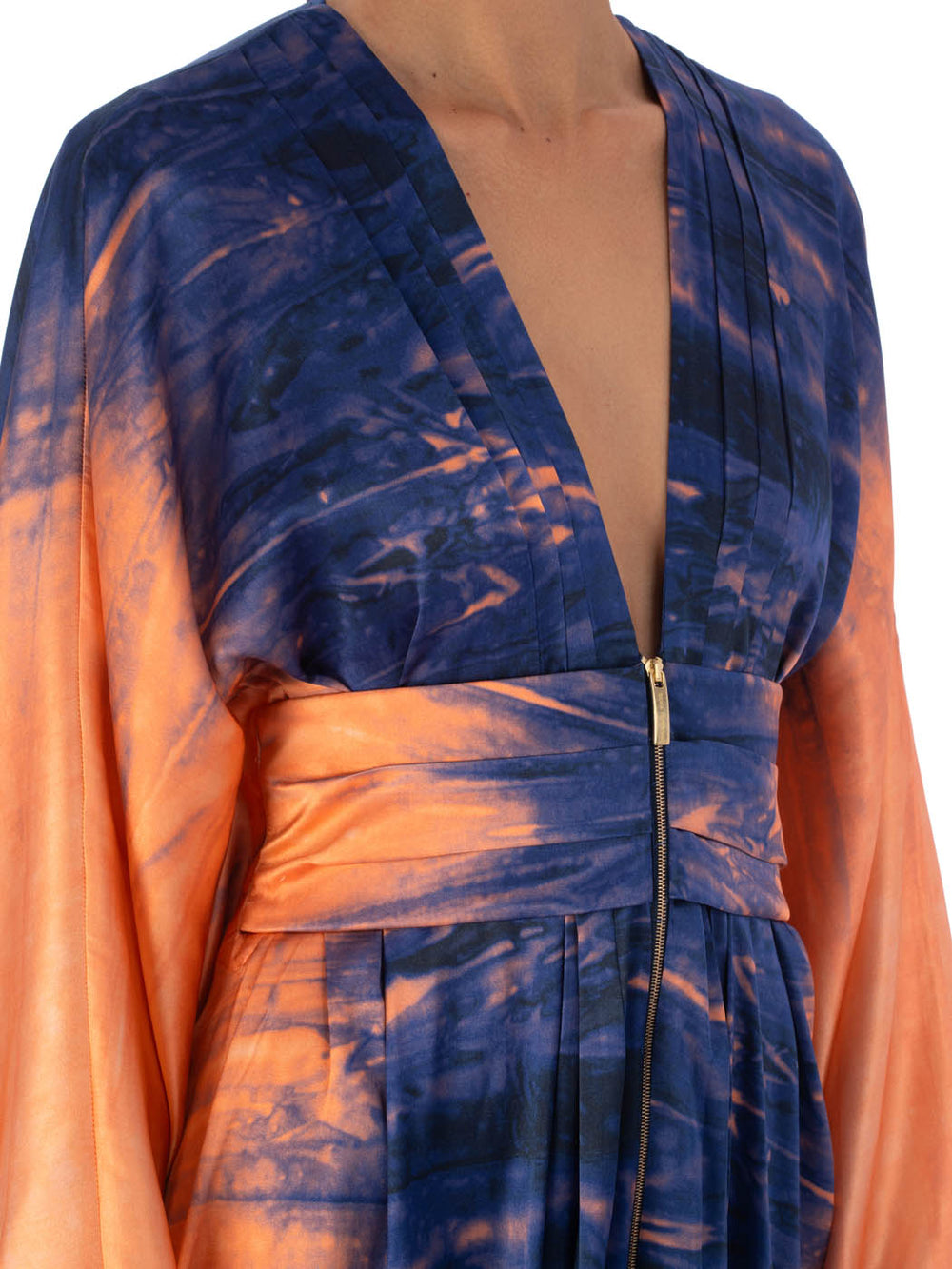 El vestido Danette Mediterranean Coral Blue es una bata con escote en V y estampado abstracto en azul y naranja. Tiene cierre de cremallera hasta la mitad, cinturilla ancha y tejido suave y fluido.