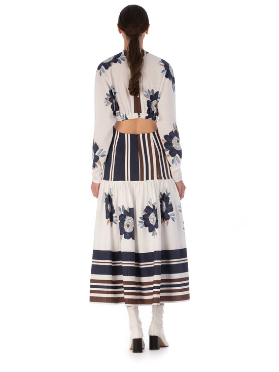 A long-sleeved Gabina Dress Multi Navy Brown Floral featuring a white base with blue floral patterns and horizontal navy stripes, designed with a flared skirt, isolated on a white background.